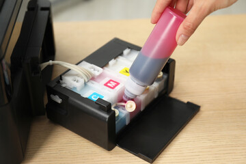 Woman refilling ink in modern printer at workplace indoors, closeup