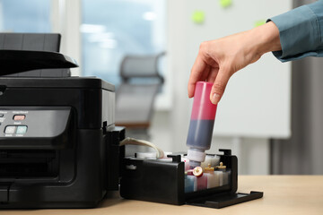 Woman refilling ink in modern printer at workplace indoors, closeup