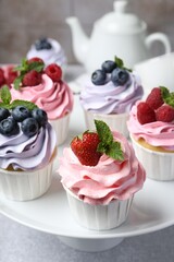 Tasty cupcakes with different berries on light grey table, closeup