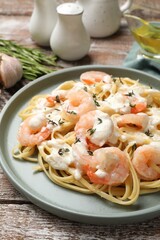 Delicious pasta with shrimps served on wooden table, closeup