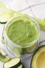 Delicious green smoothie and ingredients on white table