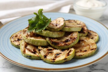 Tasty grilled zucchini slices with parsley on white marble table, closeup