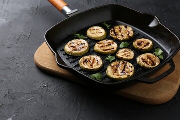 Tasty grilled zucchini slices with parsley in frying pan on grey textured table