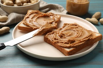 Tasty sandwiches with peanut butter and nuts on light blue wooden table, closeup