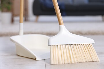 Cleaning broom and dustpan on wooden floor indoors