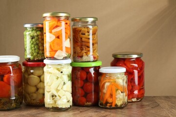 Different pickled products in jars on wooden table