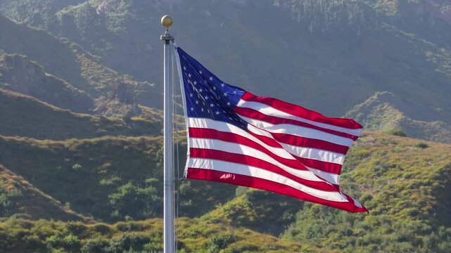 An American flag is proudly waving against a mountainous backdrop, symbolizing patriotism, freedom, and national pride. The highquality 4K image captures this scene during a serene sunset or sunrise