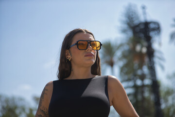 Portrait of young woman, brunette, beautiful, very tattooed, with black jumpsuit and glasses with...