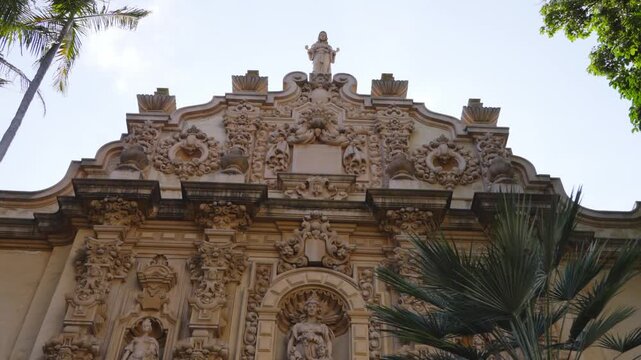The intricate baroque facade of the Casa del Prado Theater in Balboa Park is a masterpiece of Spanish colonial revival architecture, adorned with detailed carvings and surrounded by lush greenery.