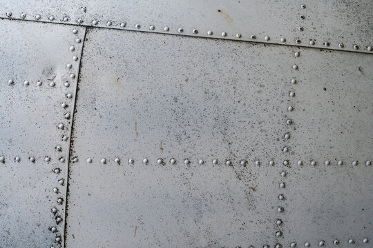 Background, texture of the metal skin of an aircraft in gray or steel color with rivets