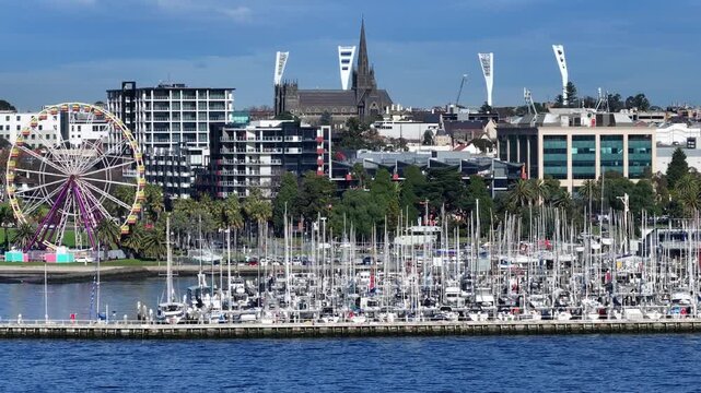 A ferris wheel in a bustling city harbor enhances the skyline