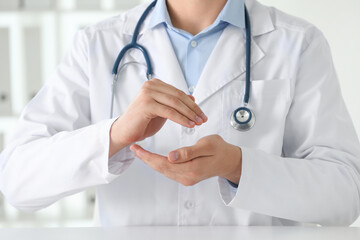 Doctor holding something at white table in clinic, selective focus