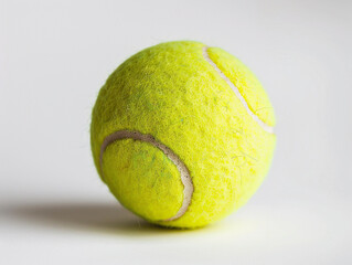Bright Yellow Tennis Ball Resting on Smooth Surface With Soft Lighting