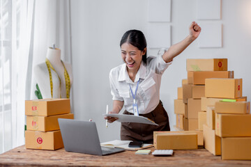 Excited happy asian woman working for smeproduction online at home with her laptop,she’s sme online seller.