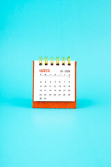 March 2025 white desk calendar on blue color background.