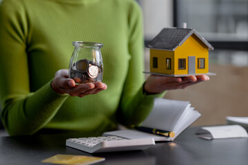 saving money, Real estate concept background. Hand of House model and coins stack on wooden table,...