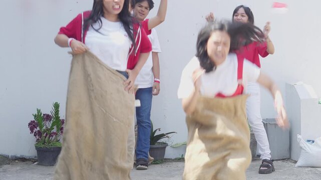 Young Asian Woman Pushing And Cheat During Sack Race Celebrating Indonesian Independence Day, August 17.