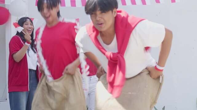 Two Asian Young Men Participate In Sack Race Called Balap Karung To Celebrate Indonesian Independence Day, August 17th.