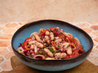 A healthy and nutritious Turkish Piyaz salad featuring white beans, tomatoes, onions, parsley, and sumac. This vegan and vegetarian dish is served in a blue bowl on a wooden board