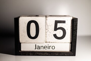 Close-up of a wooden block calendar displaying January 5th in Portuguese