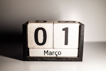 Close-up of a wooden block calendar showing March 1st in Portuguese