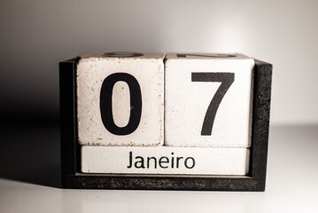 Close-up of a wooden calendar showing the date 7th of January in Portuguese