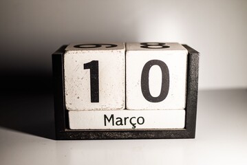 Wooden calendar blocks showing the date March 10 in Portuguese on a white background.