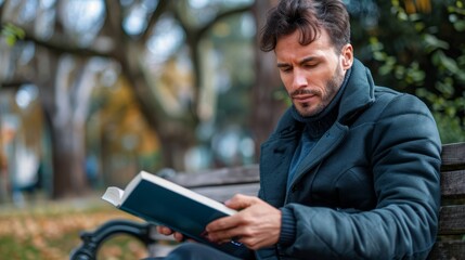 Obraz premium A man sits on a bench, book in hand, engrossed in its pages