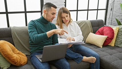 Fototapeta premium A couple reviews documents together in their modern living room, conveying a sense of partnership and home management.