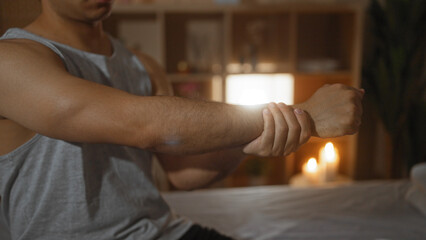 A man in a spa holds his arm in a wellness center indoors, highlighting a peaceful atmosphere with candles.