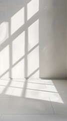Obraz premium A bright white room with light shining through the window, casting soft shadows on an empty wall. creating an abstract and minimalist background for product display or presentation