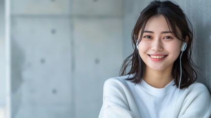 Obraz premium A woman in headphones, leaned against a wall, hands on hips, smiling at the camera