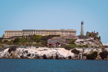 Fototapeta premium Alcatraz Island with its iconic prison and lighthouse surrounded by greenery and rocky terrain. The second image is a black and white photo of the Golden Gate Bridge with hills in the background. The 
