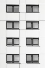 Fototapeta premium A minimalist photograph featuring a repeating sequence of industrial windows on a modern building, creating a rhythmic pattern that emphasizes both unity and variation. The image explores the balance 