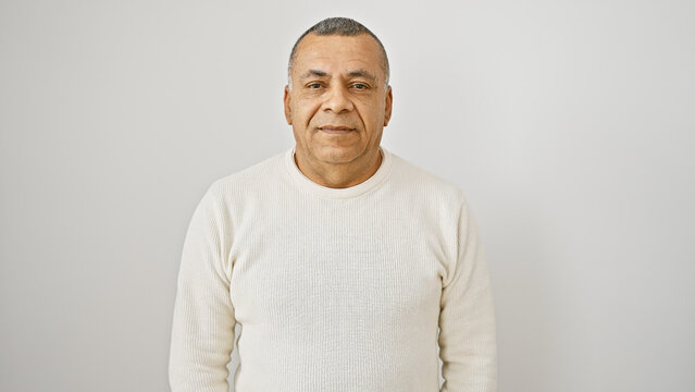 Mature hispanic man in a white sweater posing against an isolated white background, exuding confidence and approachability.