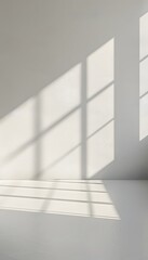 Obraz premium A bright white room with light shining through the window, casting soft shadows on an empty wall. creating an abstract and minimalist background for product display or presentation
