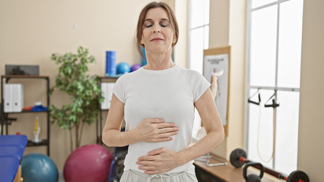 Middle-aged woman practicing relaxation techniques indoors at a physiotherapy clinic.