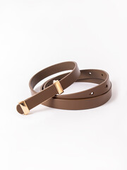 Thin brown leather women's belt with gold buckle on white background. Genuine leather accessories
