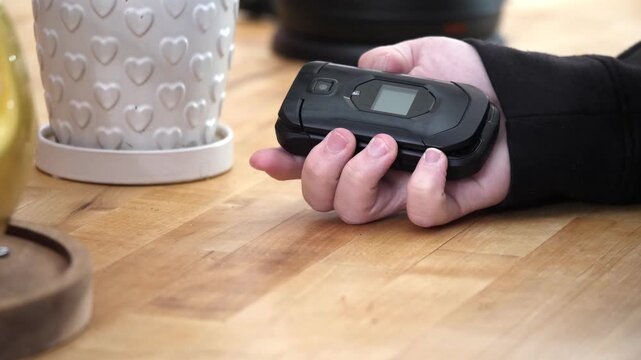 Closeup shot of someone opening a flip phone and pressing a few buttons in slow motion