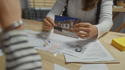 Woman detective analyzes evidence, including a photograph and documents, at an office.