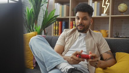 Handsome african american man playing video games in a cozy living room © Krakenimages.com
