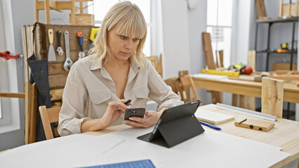 Focused woman using smartphone in indoor woodworking workshop