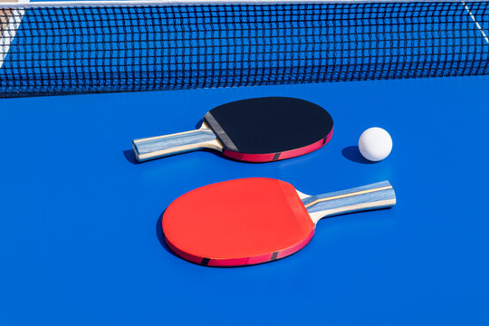 Two colorful table tennis rackets and ball on blue background