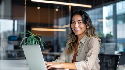 Fototapeta premium A beautiful professional woman uses a laptop in a modern office