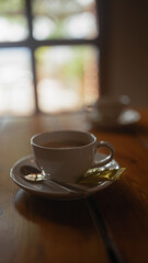 A white cup of steaming coffee on a wooden table with a blurred background in a cozy atmosphere.
