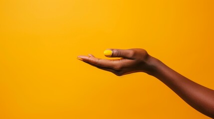 Fototapeta premium A woman's hand, holding a yellow ball, against a yellow background Simultaneously, a black hand presents a matching yellow ball