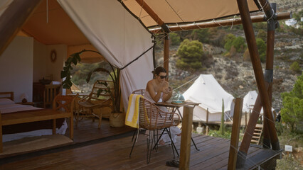 A beautiful young hispanic woman relaxes outdoors in a luxurious camping tent in africa.