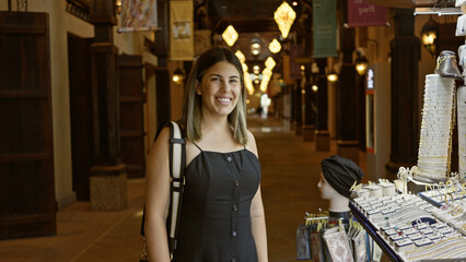 Smiling woman exploring a traditional dubai souk with lanterns, jewelry, and arabian architecture.