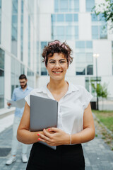 Fototapeta premium Two smiling business people going to work to modern business building