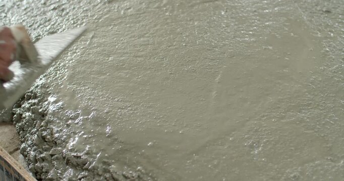 Spread the cement with Plastering trovel.Hand Holding Trowel and Smoothing Out the Plastering Concrete.Pouring cement for smooth areas.Cement flooring instead of ground.